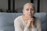 Encuentran un factor de riesgo de alzhéimer independiente de la edad Mujer mayor apoya la barbilla en sus manos cruzadas en actitud pensativa