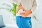 Alteraciones en el microbioma aumentan el riesgo de cálculos renales Mujer se toda la zona lumbar y el costado izquierdo doloridos