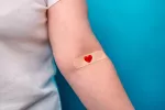 Mujer mostrando el brazo con una tirita ensangrentada por una analítica