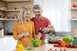 La dieta mediterránea rica en AOVE ayuda a reducir síntomas depresivos Una pareja echando aceite de oliva virgen extra a la ensalada que están preparando