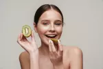 Comer kiwis mejora la vitalidad y el estado de ánimo en solo 4 días Chica joven con una gran sonrisa comiendo kiwis