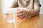 Un fármaco para el cáncer podría ayudar a tratar también el párkinson Mujer con temblores en la mano intentando coger un vaso de agua