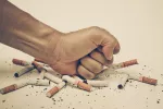 Dejar de fumar antes de los 40 iguala la esperanza de vida con un no fumador Puño golpeando sobre un montón de cigarrillos
