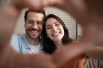 Pareja mimetizada y satisfecha Pareja haciendo el símbolo del corazón con las manos