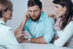 Los hombres poco fértiles y sus familiares tienen más riesgo de cáncer Hombre infértil siendo consolado por su pareja y la doctora