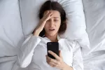 Ortosomnia, la obsesión por dormir bien que te quita el sueño Mujer mirando con angustia el dispositivo móvil creyendo que no ha dormido suficiente