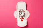 Un reloj somre una compresa simbolizando el tiempo para la próxima mestruación