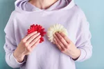 Mujer sosteniendo dos flores de distintos colores junto a su pecho