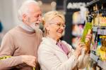 Hombre y mujer mayores examinan una botella de aceite de oliva en la tienda