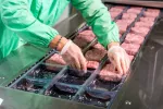 Abusar de ultraprocesados cárnicos o de desayuno resta años de vida Trabajador en una línea de producción de carne ultraprocesada