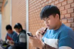 Abusar de las redes sociales eleva el riesgo de fumar en niños y jóvenes Adolescente fumando mientras mira su teléfono móvil