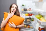 Una dieta rica en frutas y verduras puede mejorar la calidad del sueño Chica con almohada en la mano bosteza junto a la nevera abierta