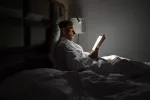Revelan por qué los noctámbulos tienen más riesgo de trastornos mentales Persona joven leyendo por la noche en la cama