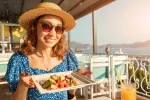 Revelan por qué las mujeres que siguen la dieta mediterránea viven más Mujer comiendo una ensalada de verano junto al mar