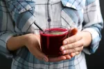 El jugo de remolacha protege la salud cardíaca en mujeres posmenopáusicas Mujer sosteniendo una taza con zumo de remolacha