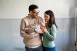 El padre contribuye a la microbiota del bebé en su primer año de vida Un padre sosteniendo en brazos a su bebé junto a su pareja