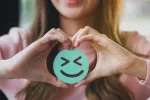 Niveles elevados de serotonina ayudan a afrontar mejor información negativa Mujer joven sonríe sosteniendo un emoji feliz