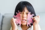 Los síntomas del COVID persistente son diferentes en niños y adolescentes Niño rompiendo una silueta del virus COVID-19 hecha en papel