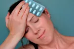 Una mujer con dolor de cabeza sosteniendo un blister de pastillas