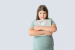 Nuevo fármaco ofrece esperanza para tratar la obesidad infantil Niña con obesidad sujeta con tristeza una báscula