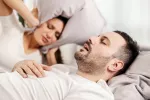 Fármaco prometedor para la apnea del sueño, la afección de los ronquidos Mujer se tapa con la almohada por los fuertes ronquidos de su pareja