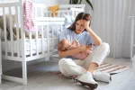 Madre deprimida sentada con su bebé junto a la cuna