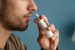 Un aerosol nasal sin fármacos puede proteger contra gripe, COVID o catarro Hombre joven usando un aerosol nasal