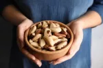 Las nueces de Brasil reducen la inflamación en mujeres con sobrepeso Mujer sosteniendo un cuenco con nueces de Brasil