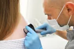 Una terapia pionera en España cura el cáncer de piel con un radiofármaco Oncólogo observando la piel de una paciente