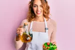 Revelan el potencial del aceite de oliva virgen para combatir el cáncer Mujer mostrando un recipiente con aceite de oliva virgen para aliñar una ensalada