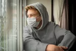Los niños y adolescentes que contraen COVID tienen más riesgo de diabetes Adolescente contagiado con Covid mirando la calle desde una ventana de su habitación