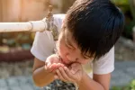 La intoxicación crónica por plomo causa déficits cognitivos en niños Niño bebiendo agua de un caño antiguo