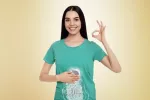 La microbiota intestinal interviene en la regulación del estrés diario Mujer tocándose el estómago y haciendo un gesto de conformidad