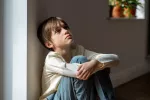 El trauma por la DANA en niños puede triplicar su riesgo de trastorno mental Niño sentado junto a la pared con la mirada perdida