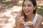 Revelan qué cantidad de pistachos comer para mejorar la salud visual Una chica joven comiendo un puñado de pistachos que sostiene en la mano