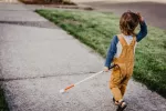 Una terapia génica prometedora para un síndrome que causa ceguera y sordera Niña pequeña caminando con un bastón