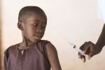 Una nueva vacuna contra la malaria muestra gran capacidad de protección Profesional sanitario con una jeringa con vacuna antipalúdica que va a inyectar a un pequeño niño para el control de la malaria