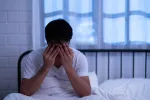 Un patrón de sueño irregular puede aumentar el riesgo de problemas cardíacos Hombre de mediana edad en la cama con problemas de insomnio
