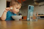 Los pediatras desaconsejan que los niños usen pantallas antes de los 6 años Niño pequeno mirando la pantalla del móvil mientra come