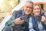 Tomar café puede aumentar la longevidad y prevenir enfermedades Dos adultos mayores y saludables sonríen sosteniendo sus tazas de café