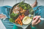 Ciertas dietas y alimentos son clave para mejorar la salud del microbioma intestinal Una mujer sostiene un plato con verduras y arroz integral