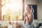 El café que tomamos por la mañana puede proteger la salud del corazón Una joven sostiene su taza de café junto a la ventana iluminada por el sol