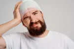 Lesiones traumáticas en la cabeza pueden reactivar virus que provocan enfermedades neurodegenerativas Hombre se toca la cabeza vendada con gesto de dolor