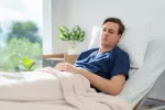 Reinfectarse con el coronavirus más de una vez aumenta el riesgo de COVID prolongado Hombre en la cama con aspecto afligido