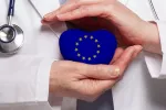 Factores genéticos en el ADN mitocondrial pueden proteger a los europeos frente al COID grave Médico sostiene en sus manos una figura de corazón con el símbolo de la Unión Europea