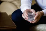 El agua con gas podría ser útil como ayuda para adelgazar Hombre sostiene en sus manos un vaso de agua con gas