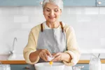 Consumo regular de huevos previene enfermedades cardiovasculares Mujer mayor prepara un plato con huevos