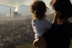 El aire contaminado causa la muerte de más de 100 niños pequeños cada día Mujer con niño en brazos observa el humo contaminante procedente de una fábrica