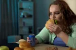 Los adolescentes que comen a última hora de la tarde o noche tienen más riesgo de engordar Adolescente cena una hamburguesa frente a la pantalla del ordenador