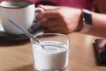Relacionan el edulcorante aspartamo con más riesgo de aterosclerosis Mano de mujer sujeta una taza de café con leche junto a un recipiente con aspartamo